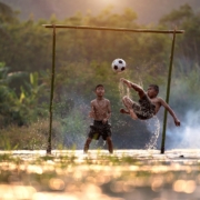 2 boys playing soccer on water during daytime