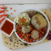a bowl of food on a cutting board next to a bowl of sauce