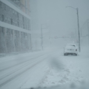 a couple of cars driving down a snow covered street