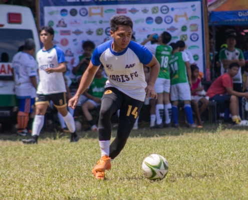 a young man kicking a soccer ball on top of a field