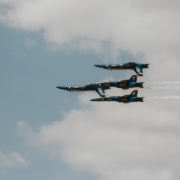four blue jet planes living contrails under white sky during daytime