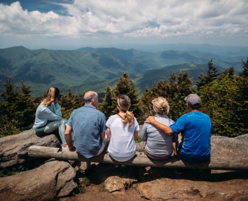 group of people sitting on rocks overlooking mountain