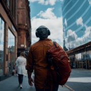 man in orange jacket walking on street during daytime