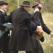 three men carrying man wearing black top
