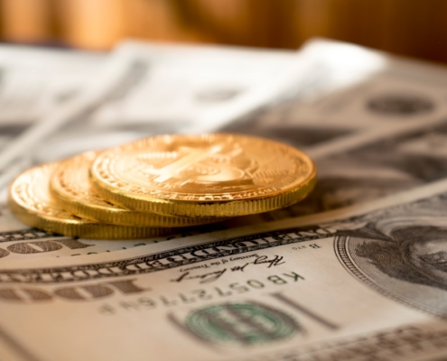 three round gold-colored coins on 100 US dollar banknotes