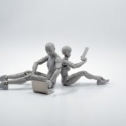 two grey plastic action figures sitting on floor back to back