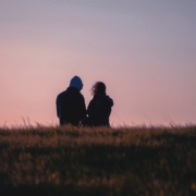 a couple of people sitting on top of a grass covered field