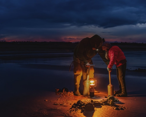 A couple of people standing on top of a sandy beach
