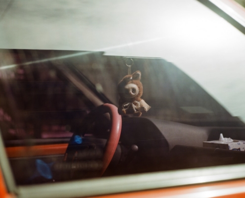 A fuzzy teddy bear hangs from a car's rearview mirror.
