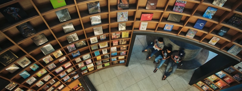 a group of people sitting on top of a book shelf
