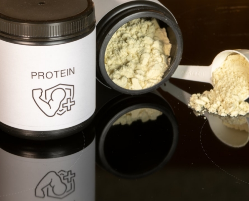 a jar of protein powder next to a spoon