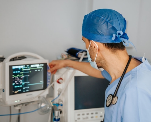 a man in scrubs and a stethoscope looking at a monitor