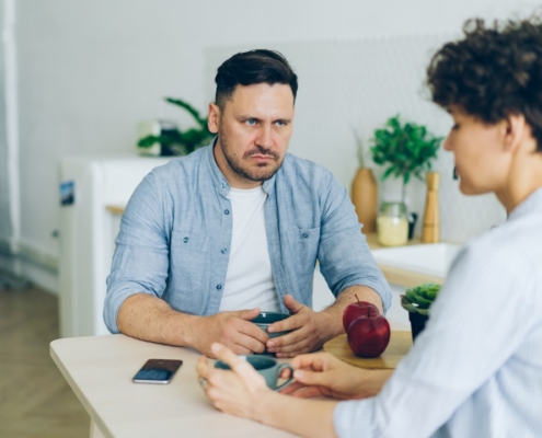 a man sitting at a table talking to a woman