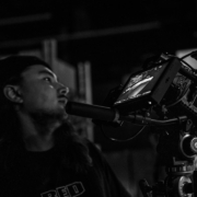 a man standing next to a camera on a tripod