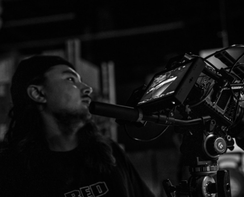 a man standing next to a camera on a tripod