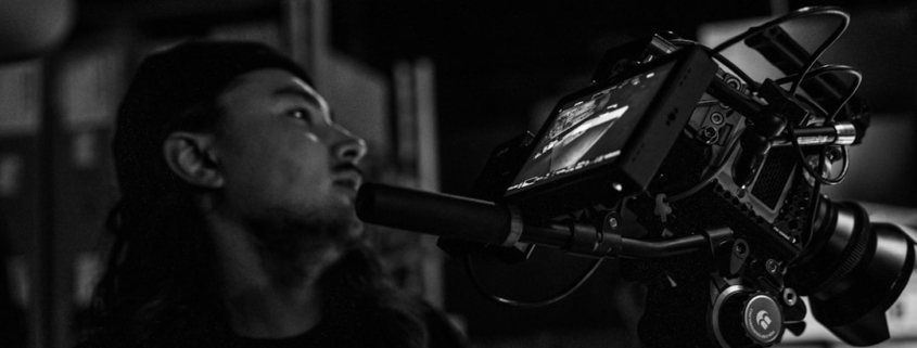a man standing next to a camera on a tripod