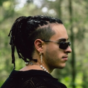 A man with dreadlocks standing in the woods
