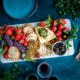 a platter of crackers, strawberries, and fruit