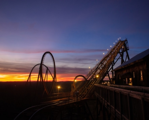 a roller coaster at sunset with the sky in the background
