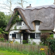 a white house with a thatched roof and a wooden fence