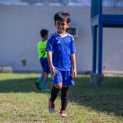 a young boy in a blue uniform playing soccer