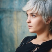 close up photography of woman wearing black sleeveless top leaning on gray concrete wall