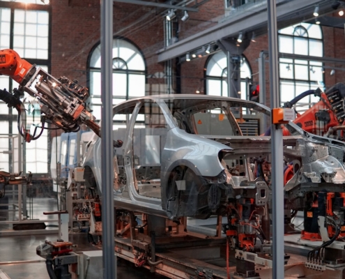 gray vehicle being fixed inside factory using robot machines
