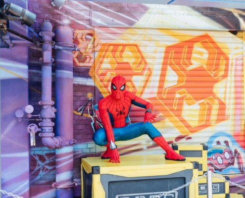 man in red jacket and blue pants sitting on yellow and gray wall