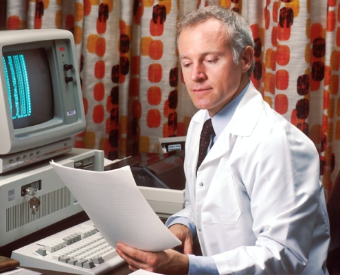 man reading papers in front of computer