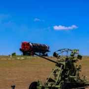 Military equipment rests under a bright blue sky.