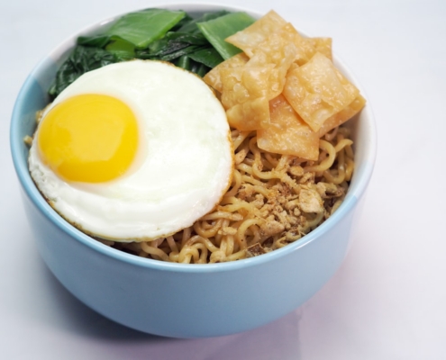 Noodles with fried egg, greens, and crispy wontons