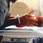 person wearing gray shirt putting baby on scale
