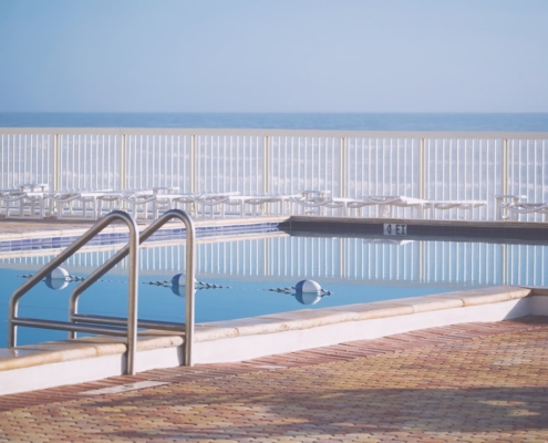 Swimming pool with ocean and chairs in background