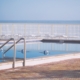 Swimming pool with ocean and chairs in background