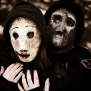 Two people wearing creepy masks and hoods