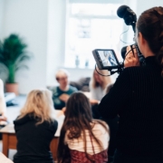 woman holding camera standing near people