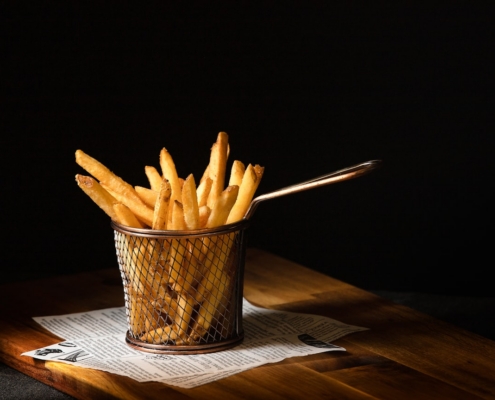 a basket of french fries sitting on top of a wooden table