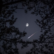 A meteor streak under the moon and stars.