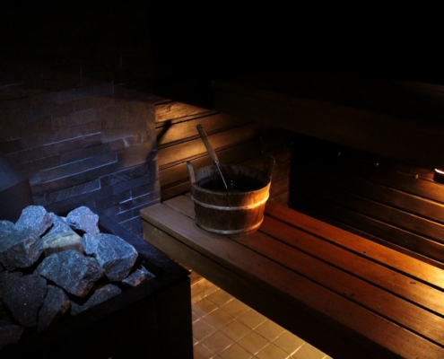 A sauna with rocks, a bucket, and wood.