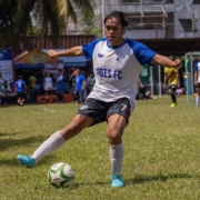 a woman kicking a soccer ball on a field