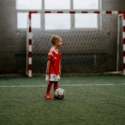 boy standing beside soccer ball near soccer net