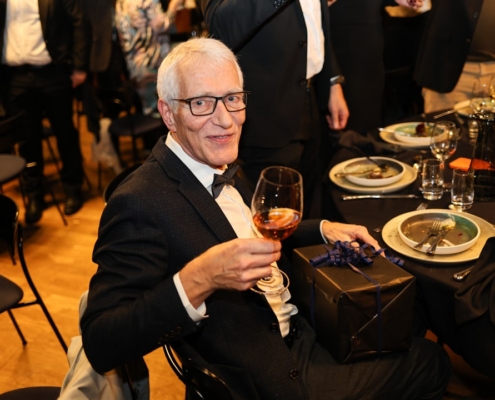 Man in tuxedo holding wine glass at formal dinner