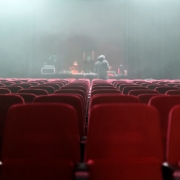 people sitting on red chairs watching a band performing on stage