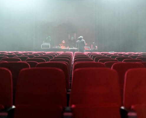 people sitting on red chairs watching a band performing on stage