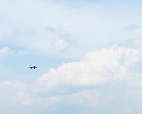 photo of white commercial airplane flying in sky under white clouds