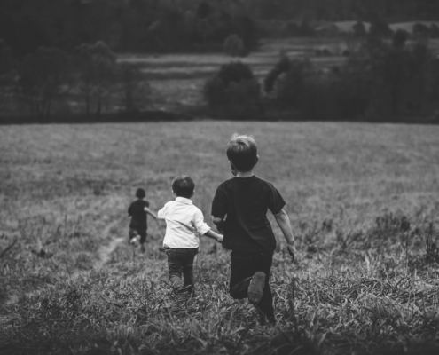 three boys running on field