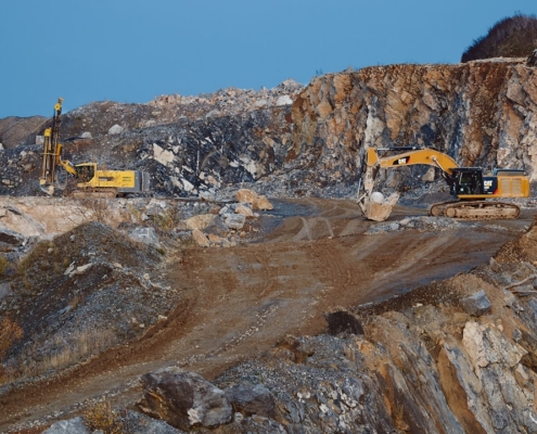 yellow and black excavator on brown rocky mountain during daytime