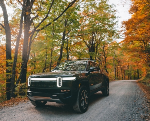 a black car parked on a road surrounded by trees