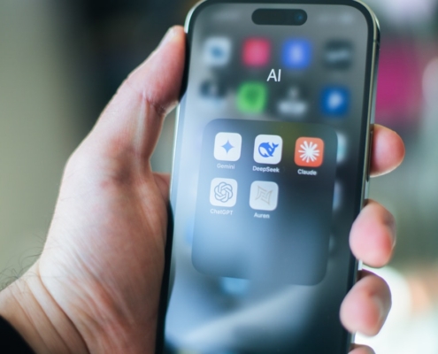A hand holds a smartphone with various apps.