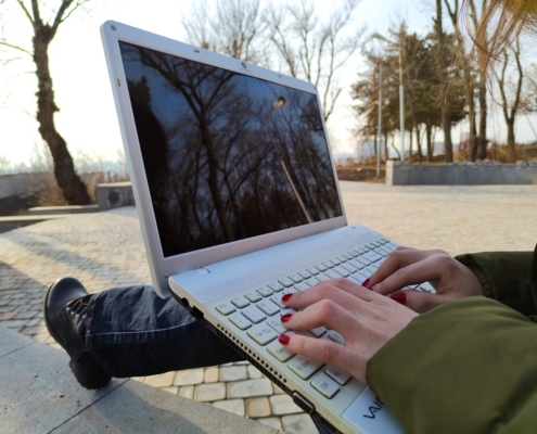 a person typing on a laptop on a bench